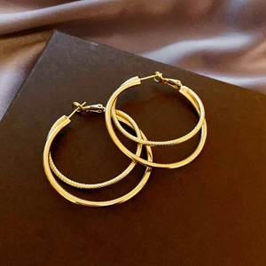 Close-up of golden double-hoop earrings featuring smooth and textured metallic layers