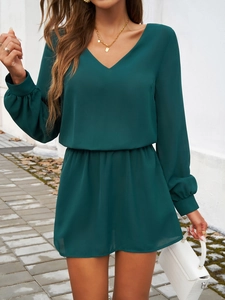 Détail d'une robe verte foncée à col en V avec des manches bouffantes et taille cintrée