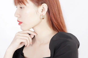 Side view macro of a large gold stainless steel hoop earring worn by a female model