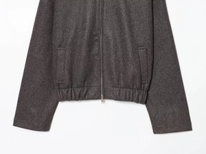 Detail of dark grey bomber jacket featuring metal zipper and ribbed elastic hemline