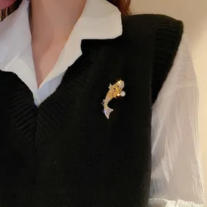 Élégante broche poisson koi plaqué or avec zircons blancs et perle sur gilet noir