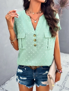 Close-up of mint green V-neck blouse with button details, pockets and textured dots
