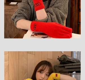 Detail of red and yellow knitted gloves with cute embroidered bow logo for winter