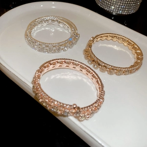 Detailed view of three-layer sparkling zircon bangles in silver, gold, and rose gold