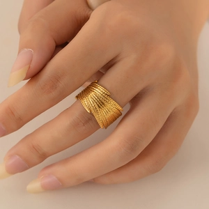 Macro shot of gold feather textured stainless steel open ring with detailed engraving