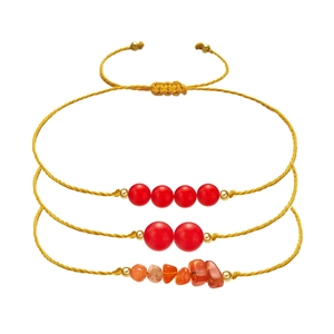 Detailed view of handmade woven bracelets with red beads and irregular orange stones