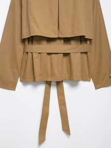 Detail of khaki cropped trench coat showing belt loops and back layered storm flap