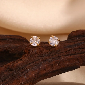Detail of 18K gold plated stud earrings with round clear zircon on dark wood