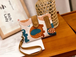 Detail of handmade canvas wallet with elephant print, leather snap and wrist strap