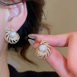 Detail of 18k gold plated pearl earrings with spiral design and zircon inlay on ear
