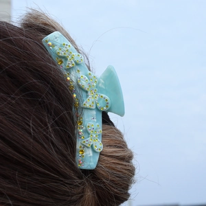 Light blue hair claw clip with colorful rhinestone butterflies worn by a model