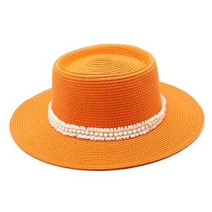 Detail of orange straw sun hat with white lace ribbon and pearl embellishments