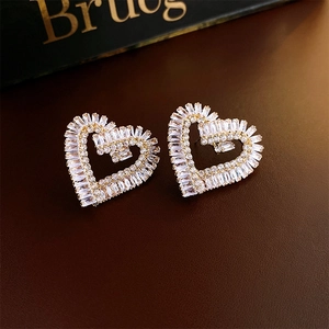 Vue macro de boucles d'oreilles cœur dorées avec zircons brillants et détails de lettres