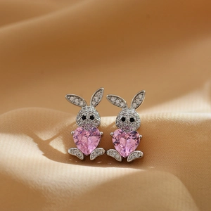 Detailed macro shot of silver rabbit earrings featuring a pink heart-shaped crystal