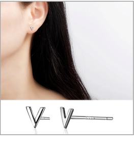 Close-up of S999 sterling silver V-shaped stud earrings showing high polish and hallmark