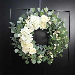 Artificial white rose and hydrangea eucalyptus wreath displayed on a black door