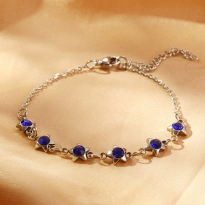 Détail du bracelet étoile en argent avec zircon bleu sur fond en satin de champagne