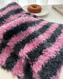 Close-up of pink and black striped knit scarf featuring soft wool texture and fringe detail