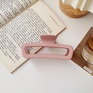 Dettaglio del fermaglio quadrato rosa opaco con una texture smerigliata su un libro