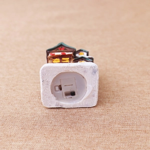 Detail of the battery compartment and power switch on a glowing resin Christmas house