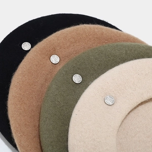 Detail showing wool felt texture and silver metal badge in black, camel, and green