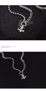 Macro shot of silver fleur-de-lis pendant with mixed chain texture on dark background