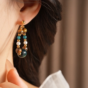 Détail de boucle d'oreille en perles avec oeil de tigre sur le mannequin