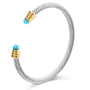 Detail view of silver cable bracelet featuring gold spiral ends and turquoise beads