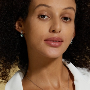 Detail of lab-grown emerald earrings and necklace on model in elegant retro silver setting