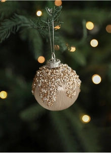 Close-up of champagne satin Christmas ball with gold sequins and beads on tree