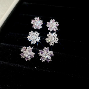 Detail view of flower stud earrings with pink, purple, and white zircon in a jewelry box