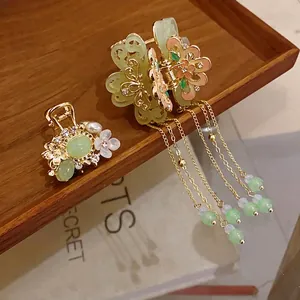 Elegant gold flower hair claw clips with pearls and green tassels in a vintage style