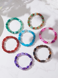 Detail of colorful cylindrical stone bracelets on marble surface with soft shadows