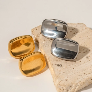 Minimalist rectangular gold and silver stud earrings on a natural stone base
