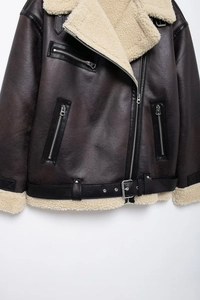 Detail of dark brown faux shearling jacket featuring wide lapels and metallic zipper accents