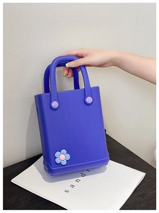 Nahaufnahme der lila EVA-Strandtasche mit blauen Blumen-Accessoires und Tragegriff