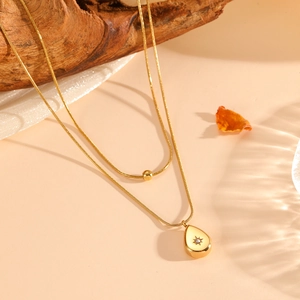 Detail of 18K gold double-layer necklace with water drop pendant and starburst engraving