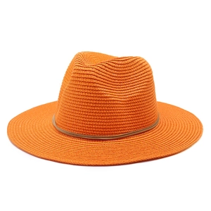 Detail of orange woven straw fedora hat featuring fine texture and dark brown trim