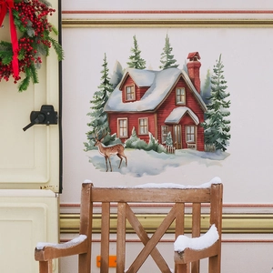 Sticker mural de Noël détaillé avec chalet rouge, sapins enneigés et rennes sur un mur
