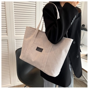 Side view of beige canvas tote bag showing spacious capacity and front pocket detail