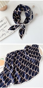 Detailed close-up of dark blue pleated silk scarf with white wavy edges and shell patterns