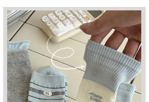 Close-up of elastic ribbed cuff on white and blue knit socks with cute animal embroidery