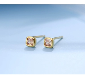Macro shot of gold square stud earrings featuring champagne crystals on blue background
