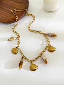 Détail de breloques coquillages dorés et pendentif texturé sur un collier à grosse maille