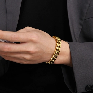 Gros plan d'un bracelet gourmette doré porté par un mannequin sur un costume chic