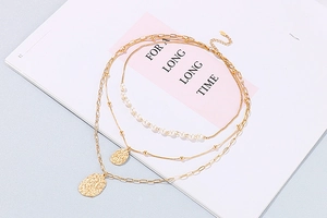 Detail of layered gold necklace with elegant pearls and hammered circular pendants