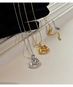 Detail of 18k gold plated rocking horse necklace featuring hammered metal and zircon stones