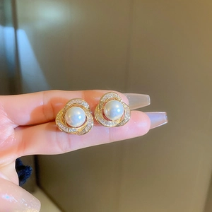 Vue détaillée de boucles d'oreilles perles vintage avec cadre tourbillon doré