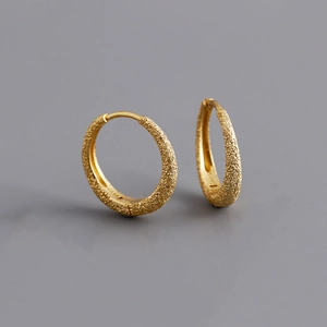 Macro shot of gold S925 silver hoop earrings with a sparkling sandblasted matte finish