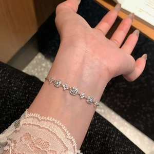 Detail of 18K gold plated clover bracelet with cubic zirconia on a female wrist